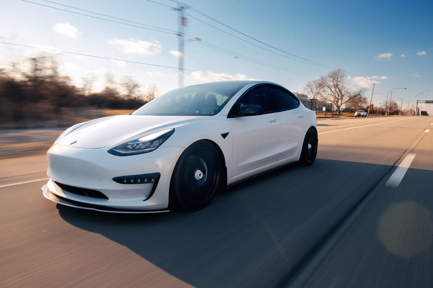 A white electric car driving on a sunny road